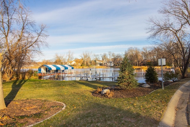 view of community featuring a water view, a dock, and a lawn