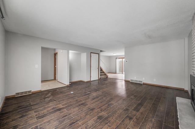 unfurnished living room featuring a large fireplace, wood-type flooring, and a textured ceiling