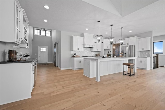 kitchen with a center island with sink, white cabinetry, stainless steel appliances, and light hardwood / wood-style floors