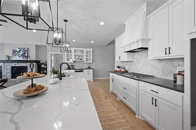 kitchen featuring light hardwood / wood-style floors, white cabinetry, dark stone countertops, and custom range hood