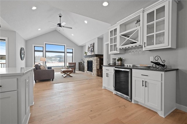 kitchen with white cabinets, light hardwood / wood-style flooring, wine cooler, and a fireplace