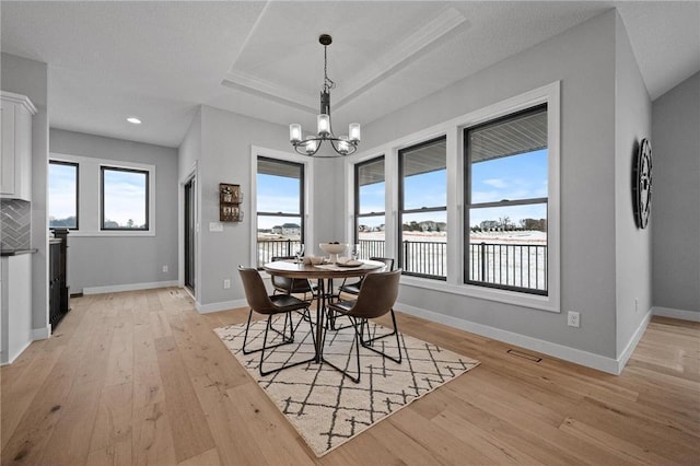 dining room with plenty of natural light, light wood-type flooring, and a chandelier