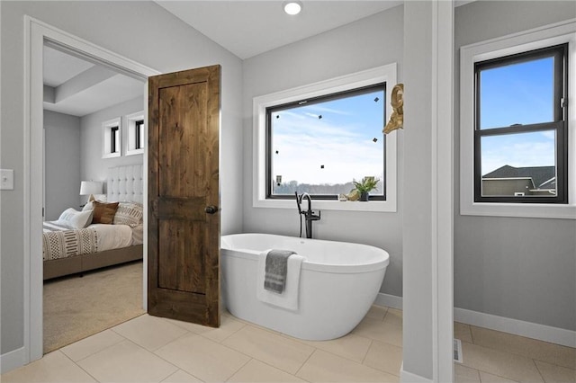 bathroom with a tub to relax in and tile patterned floors