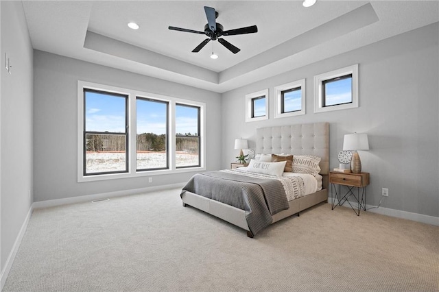 carpeted bedroom featuring a tray ceiling and ceiling fan