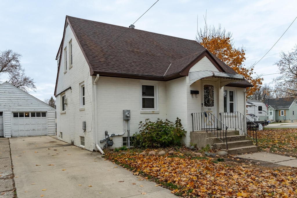 bungalow-style home featuring a garage and an outbuilding