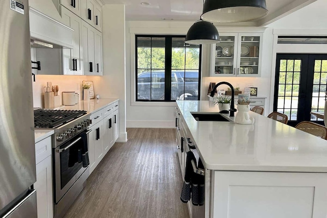 kitchen with white cabinets, french doors, stainless steel appliances, and a center island with sink