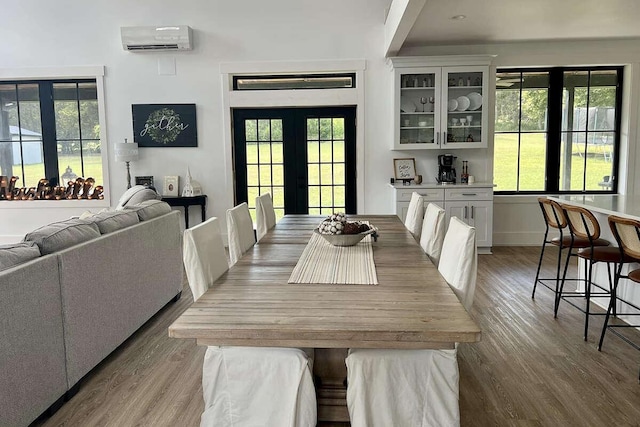 dining space featuring french doors, light hardwood / wood-style flooring, an AC wall unit, and plenty of natural light