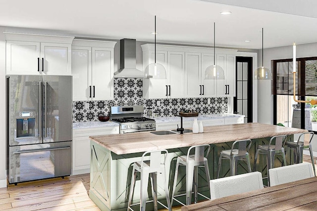 kitchen featuring a breakfast bar, wall chimney range hood, sink, an island with sink, and stainless steel appliances