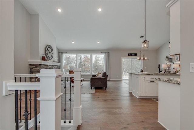 interior space with light stone counters, hardwood / wood-style floors, decorative light fixtures, a breakfast bar area, and white cabinets