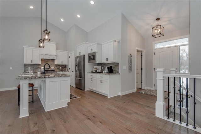 kitchen with white cabinets, pendant lighting, light wood-type flooring, and stainless steel appliances