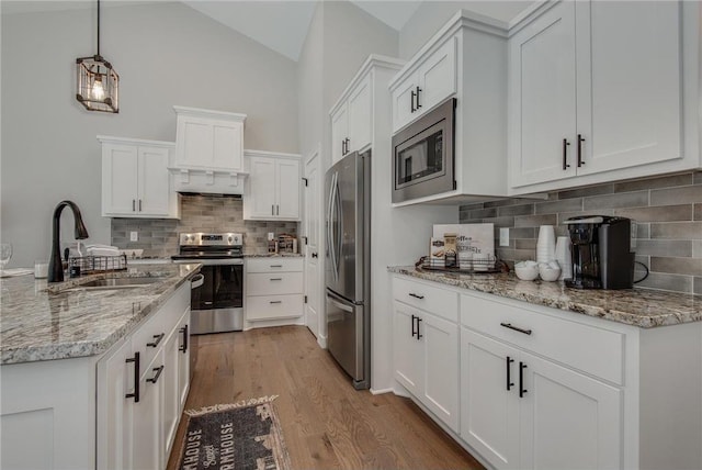 kitchen featuring sink, stainless steel appliances, light hardwood / wood-style flooring, decorative light fixtures, and white cabinets