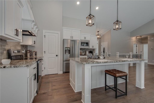 kitchen featuring dark wood-type flooring, white cabinets, a center island with sink, hanging light fixtures, and appliances with stainless steel finishes