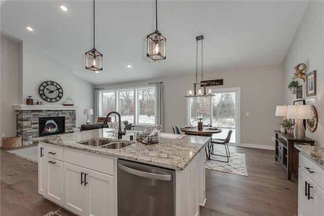 kitchen with sink, an island with sink, stainless steel dishwasher, and lofted ceiling