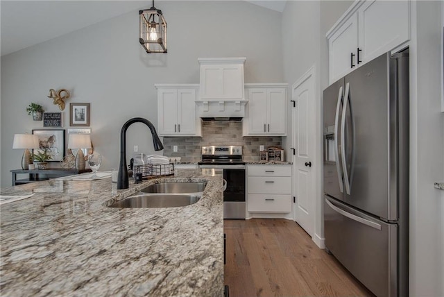 kitchen featuring stainless steel appliances, sink, light hardwood / wood-style flooring, white cabinetry, and hanging light fixtures