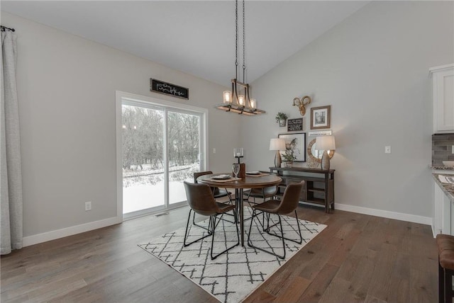 dining room with wood-type flooring and high vaulted ceiling