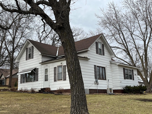 view of side of property featuring a lawn and cooling unit