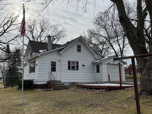 back of house with a garage and a lawn