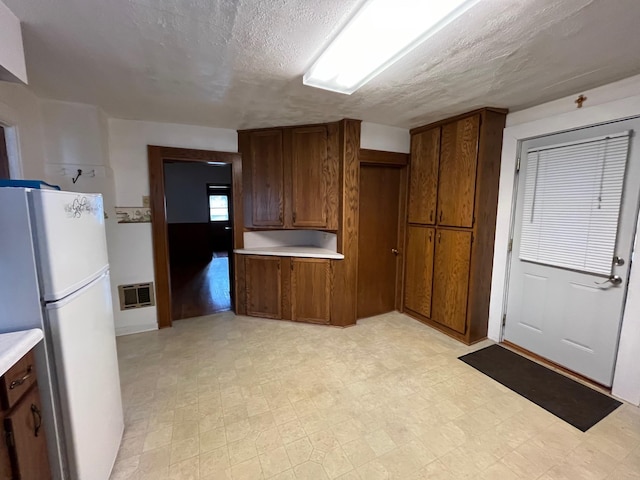 kitchen with white refrigerator, a textured ceiling, and heating unit