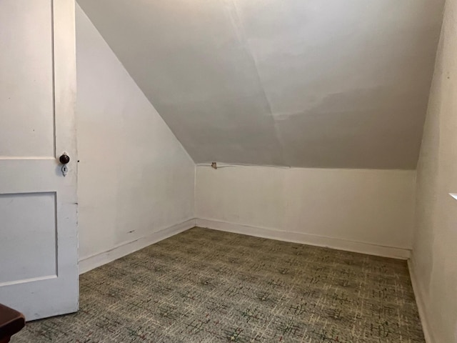 additional living space featuring vaulted ceiling and dark colored carpet