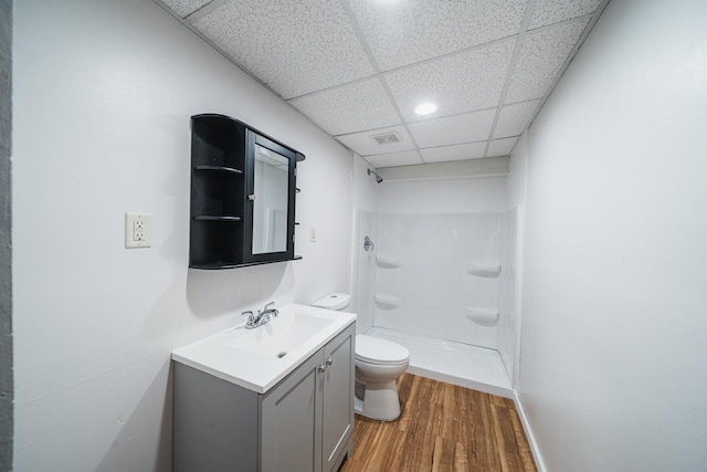 bathroom featuring toilet, hardwood / wood-style floors, a paneled ceiling, walk in shower, and vanity