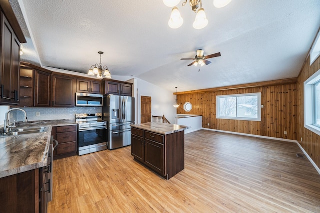 kitchen featuring vaulted ceiling, appliances with stainless steel finishes, dark brown cabinets, and decorative light fixtures