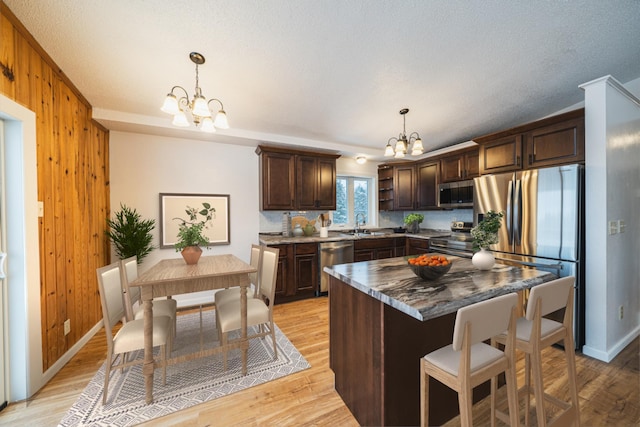 kitchen with hanging light fixtures, appliances with stainless steel finishes, a chandelier, and a kitchen island