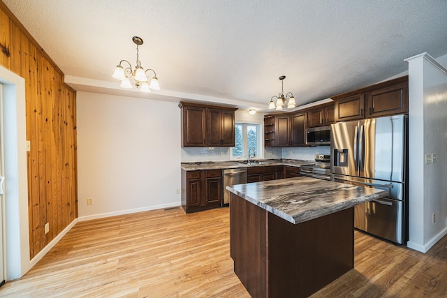 kitchen featuring an inviting chandelier, stainless steel appliances, decorative light fixtures, and a center island