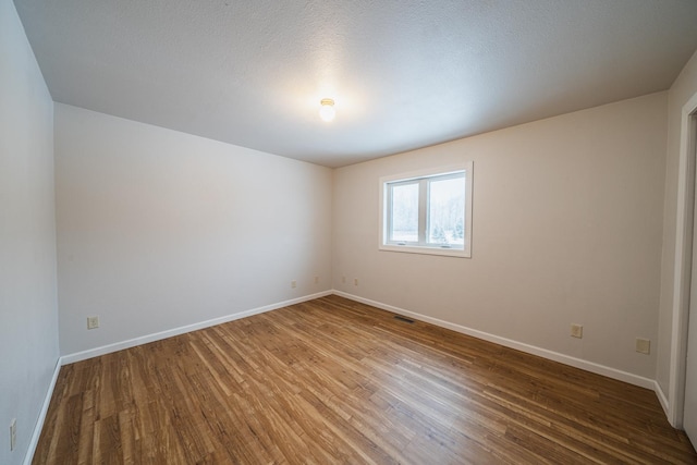 unfurnished room featuring a textured ceiling and hardwood / wood-style floors