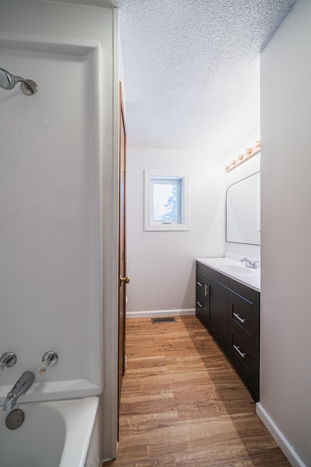 bathroom featuring vanity, washtub / shower combination, a textured ceiling, and hardwood / wood-style floors