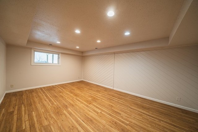 unfurnished room with a textured ceiling, hardwood / wood-style floors, and wooden walls