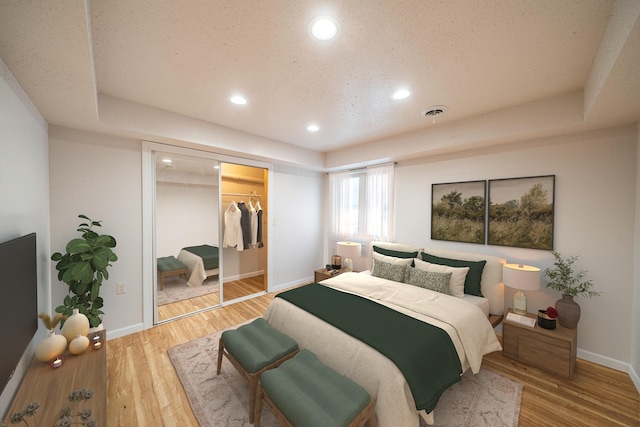 bedroom featuring a spacious closet, a closet, wood-type flooring, and a tray ceiling