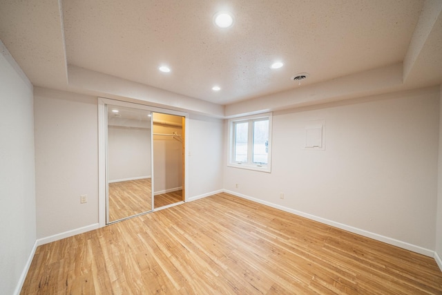 unfurnished bedroom with hardwood / wood-style flooring, a textured ceiling, and a closet