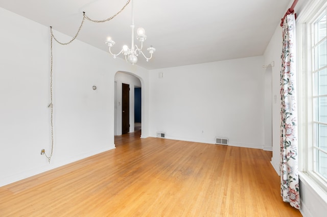 spare room with hardwood / wood-style flooring and an inviting chandelier