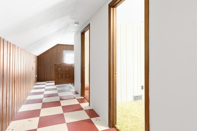 corridor featuring wooden walls and lofted ceiling