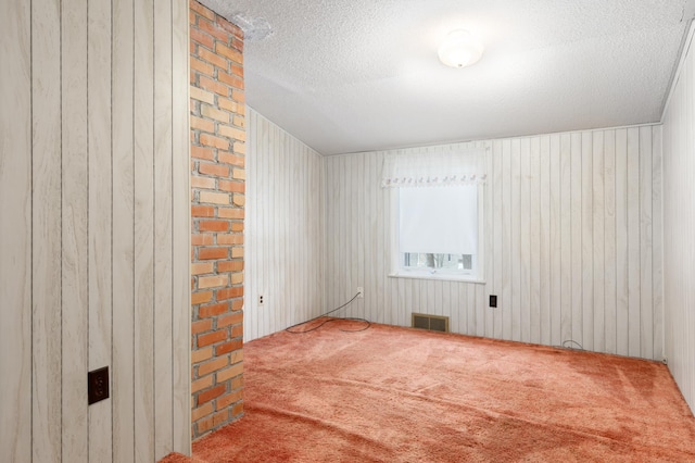 empty room featuring a textured ceiling and wood walls