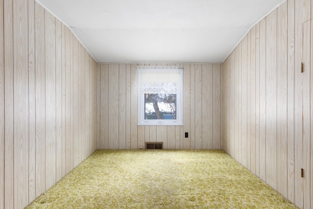 carpeted spare room featuring wooden walls