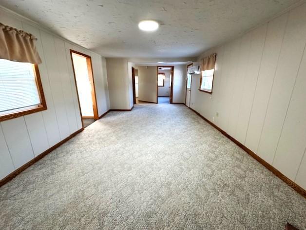 spare room featuring light carpet, a textured ceiling, and an AC wall unit