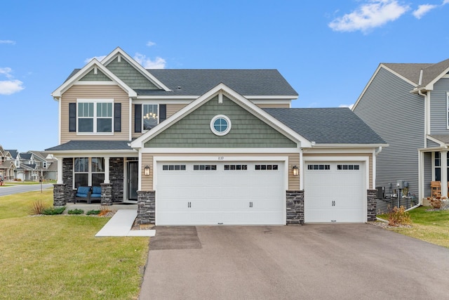 craftsman-style home featuring a front yard, covered porch, and a garage