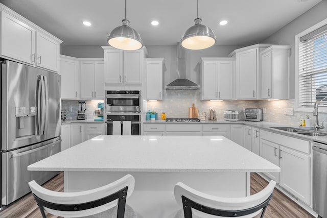 kitchen featuring white cabinets, wall chimney exhaust hood, sink, and stainless steel appliances