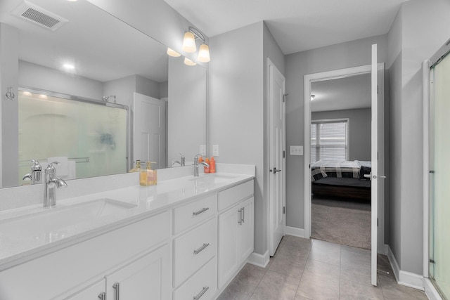 bathroom with a shower with shower door, vanity, and tile patterned floors