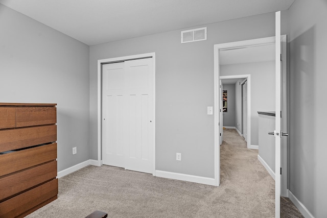 unfurnished bedroom with light carpet and a closet