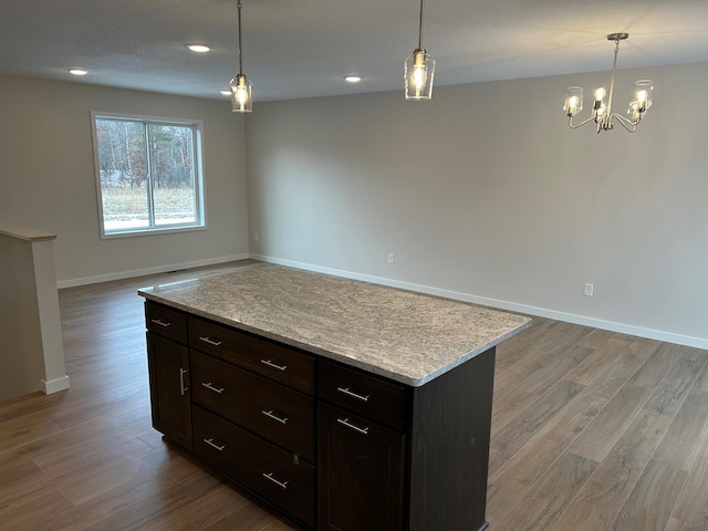 kitchen featuring light wood-type flooring, dark brown cabinetry, pendant lighting, an inviting chandelier, and a center island