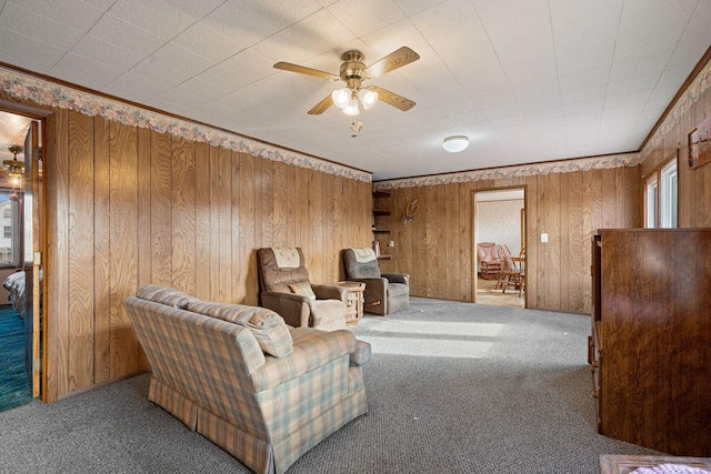 carpeted living room featuring ceiling fan, wood walls, and ornamental molding