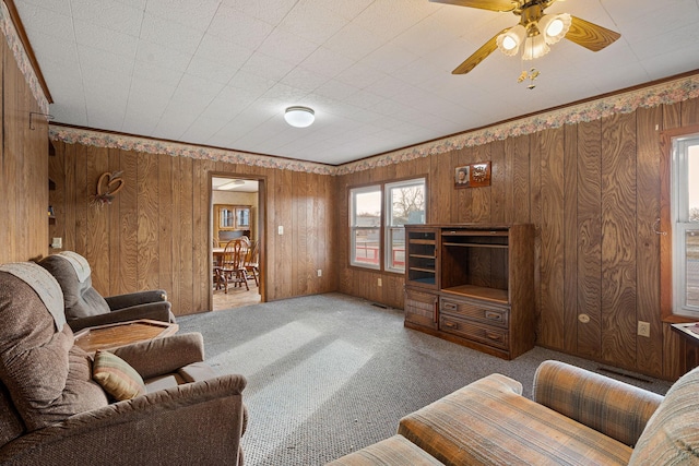 living room with carpet flooring, ceiling fan, and wood walls