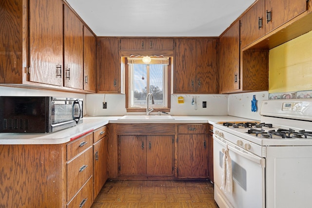 kitchen with dark parquet floors, sink, and gas range gas stove