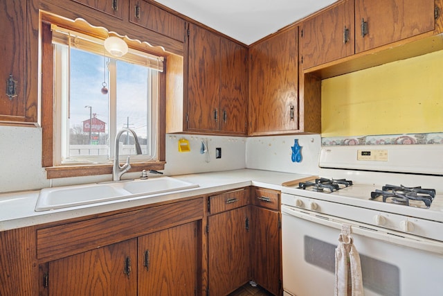 kitchen featuring tasteful backsplash, sink, and white range with gas stovetop