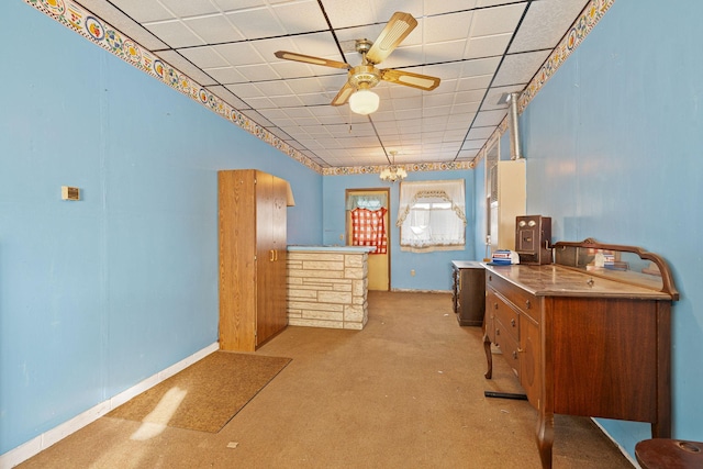 carpeted office with ceiling fan with notable chandelier and a drop ceiling