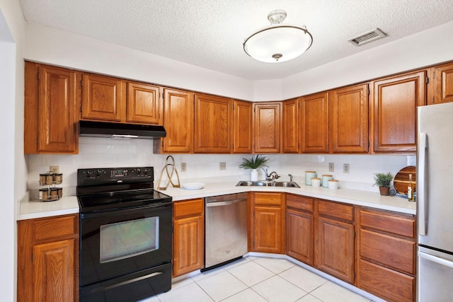 kitchen featuring appliances with stainless steel finishes, a textured ceiling, tasteful backsplash, and sink