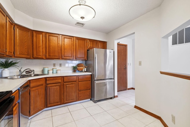 kitchen with sink, decorative backsplash, light tile patterned floors, a textured ceiling, and stainless steel appliances