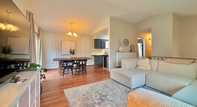 living room with a chandelier, light hardwood / wood-style flooring, and vaulted ceiling